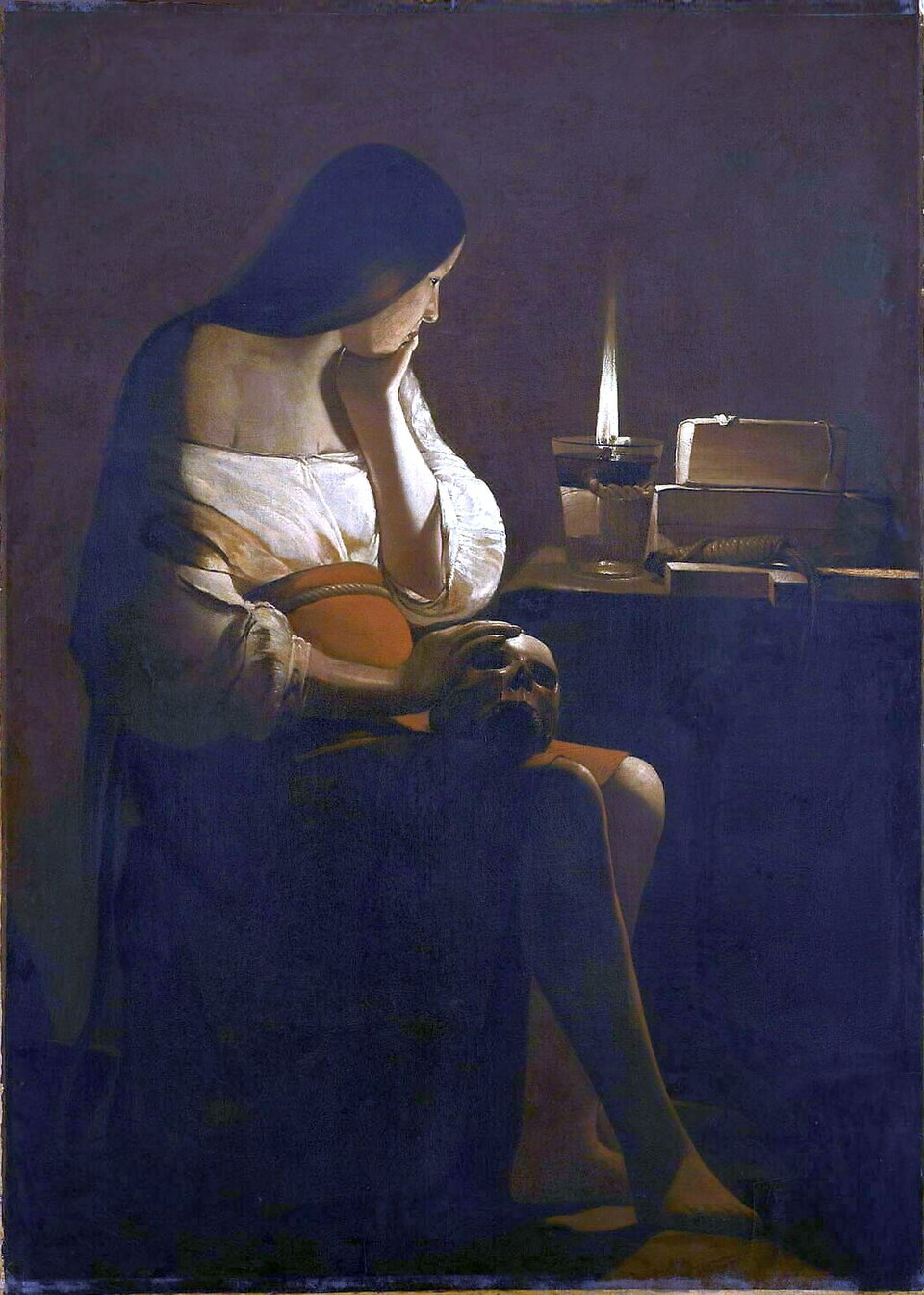 Une femme assise dans l'obscurité, la main posée sur un crâne, regarde la flamme d'une lampe