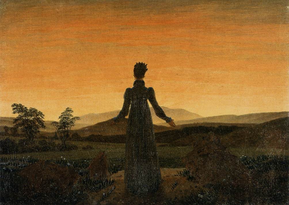 Une femme de dos, les bras ouverts, face au soleil bas